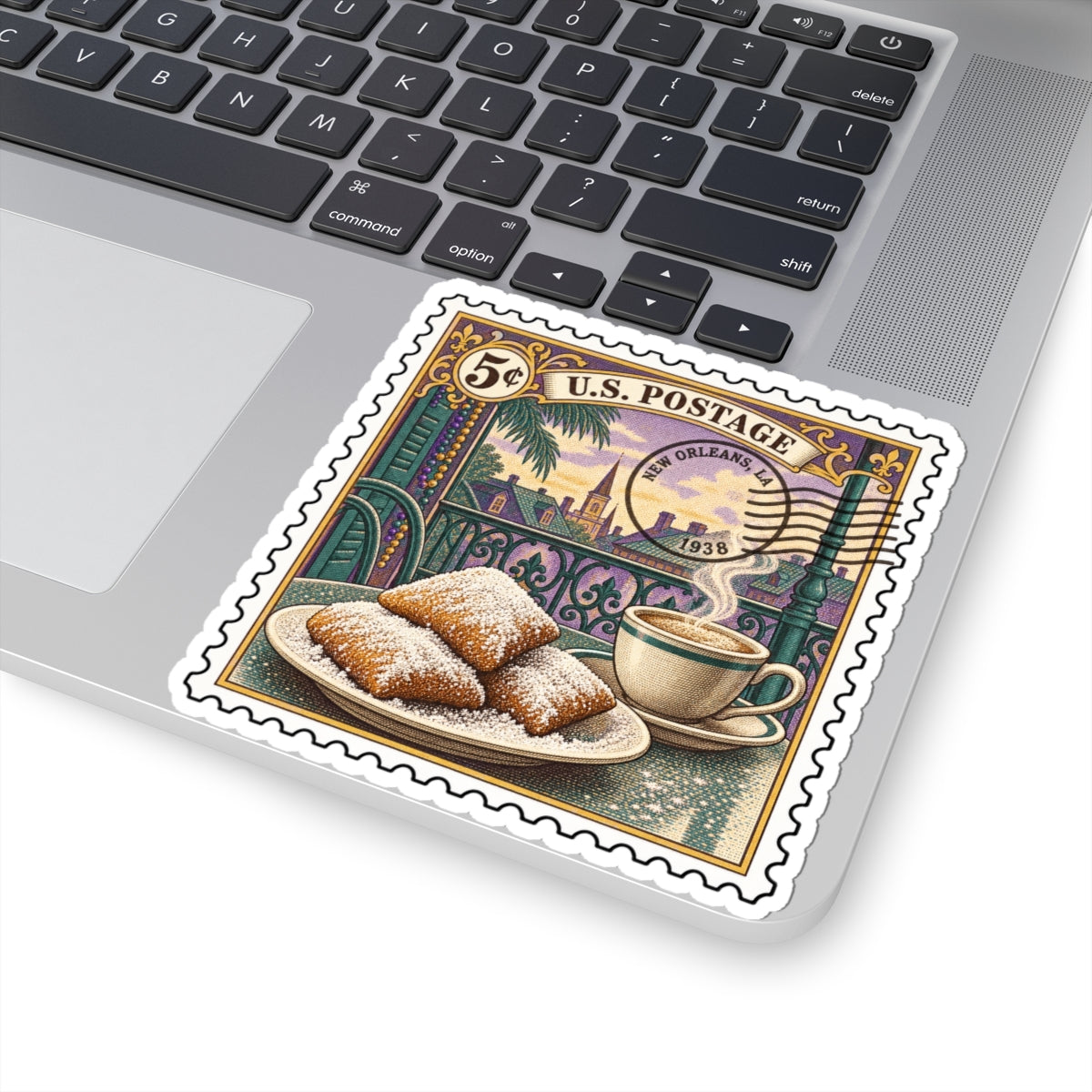 Kiss-cut vinyl sticker on laptop, vintage postage stamp art with powdered beignets and coffee