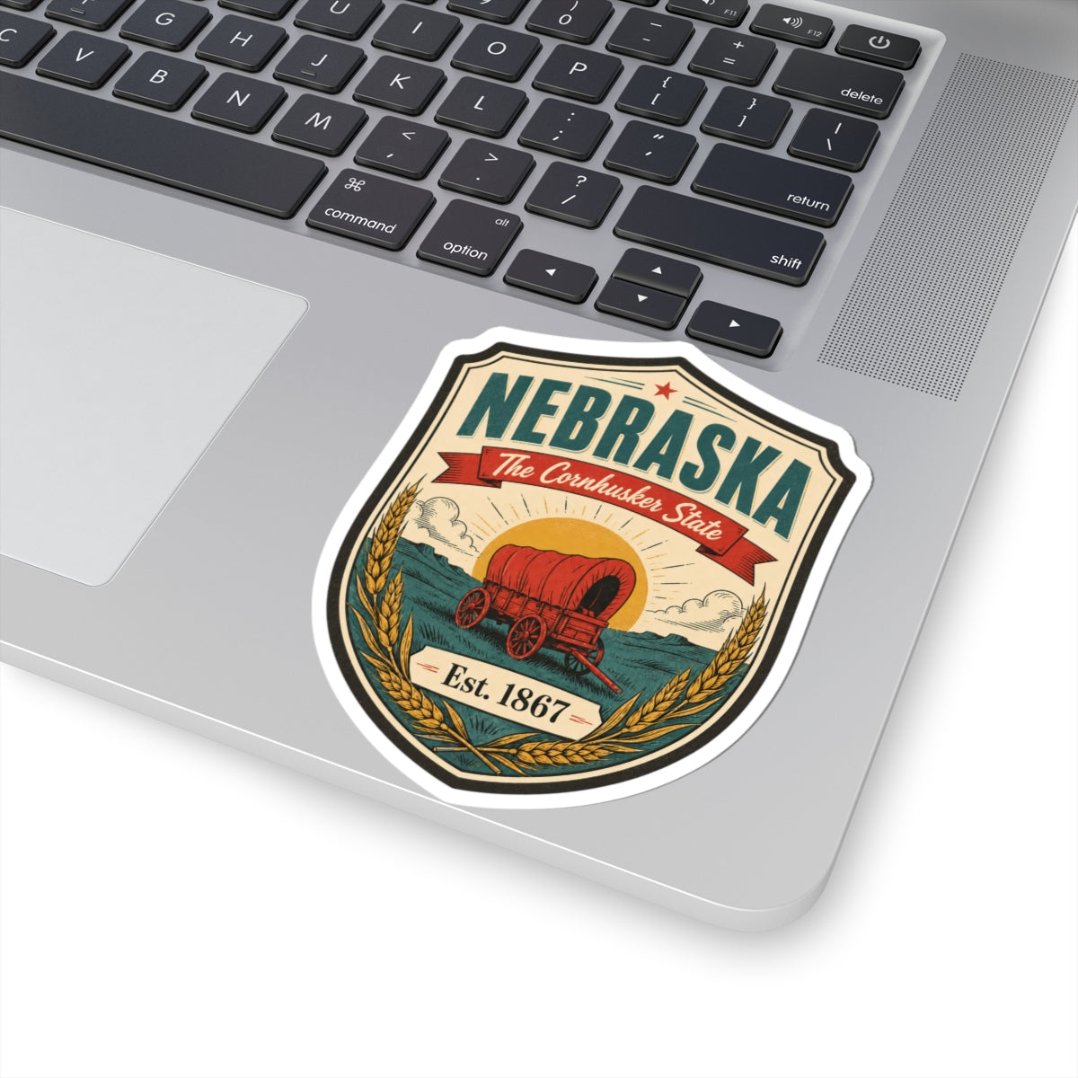Nebraska shield sticker on laptop, red covered wagon graphic and Est. 1867 text