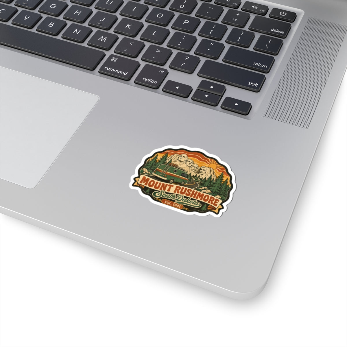 Mount Rushmore vintage road trip sticker with orange mountains and pine trees