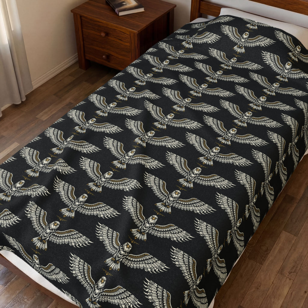 Velveteen plush blanket on bed, winged skull repeat pattern in gold on dark fabric
