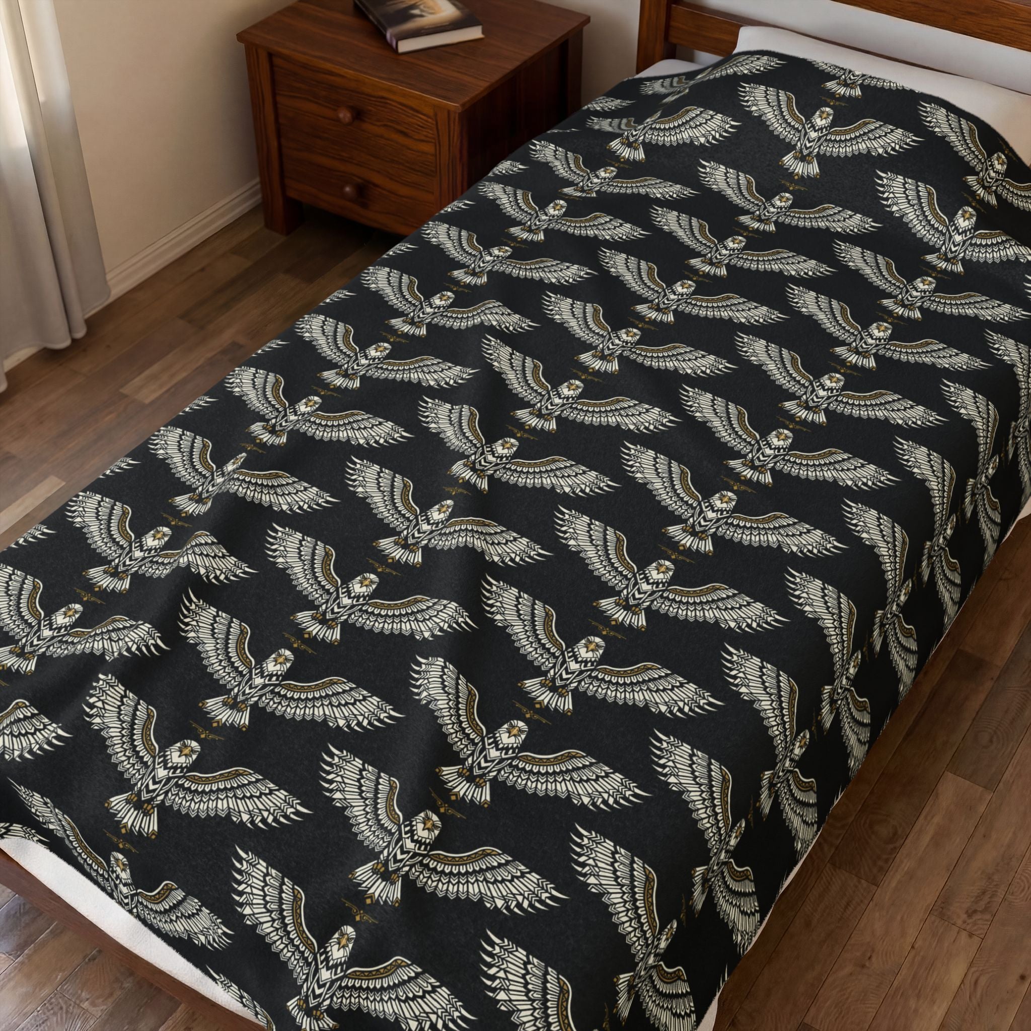 Velveteen plush blanket on bed, winged skull repeat pattern in gold on dark fabric