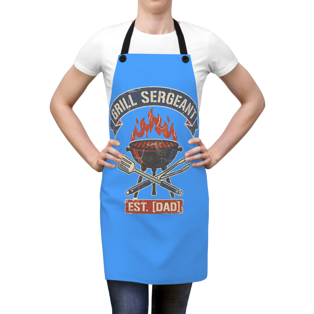 Blue grilling apron worn over white T-shirt with black neck and waist straps