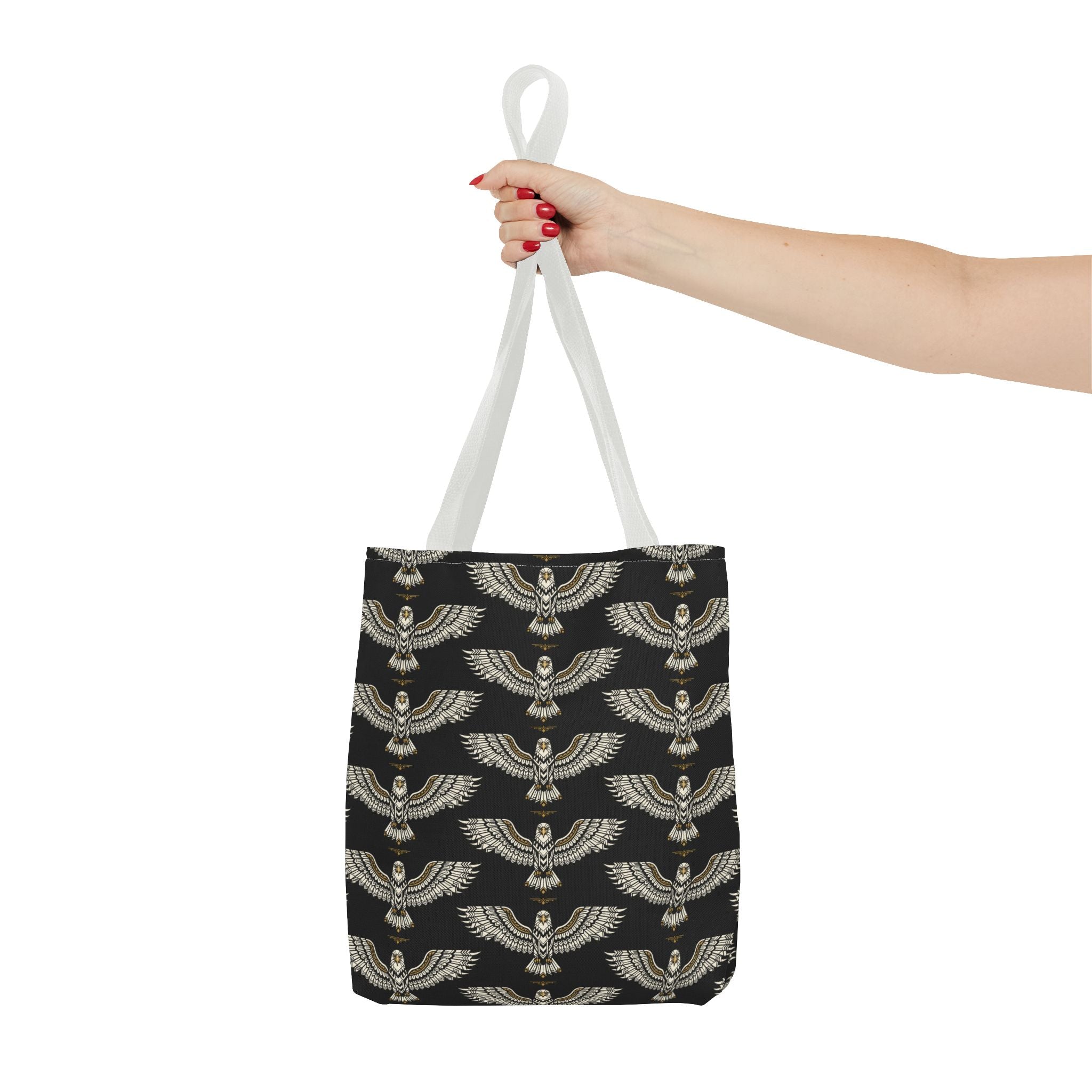 Tote bag being held by the top handles: black and gold winged scarab pattern, white