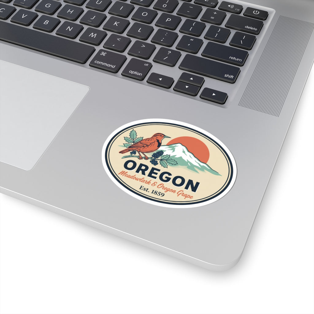Oval Oregon badge sticker on a laptop, with meadowlark, mountains, grapes, and Est. 1859.