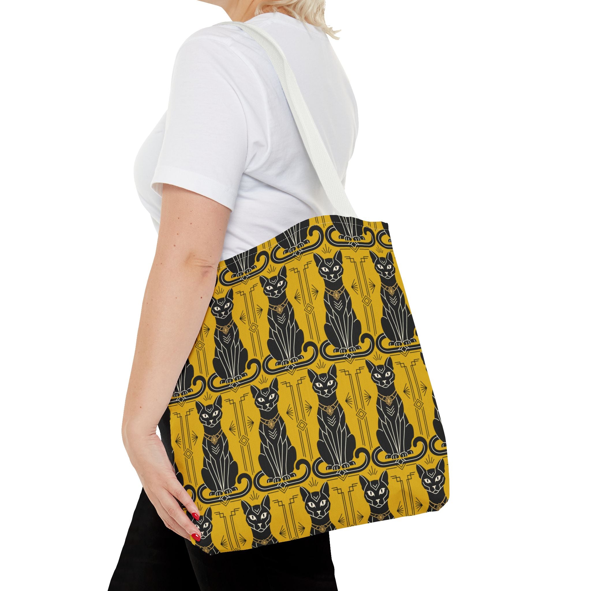 Yellow tote bag with repeating black cat pattern and navy swirls, carried at side, white strap.