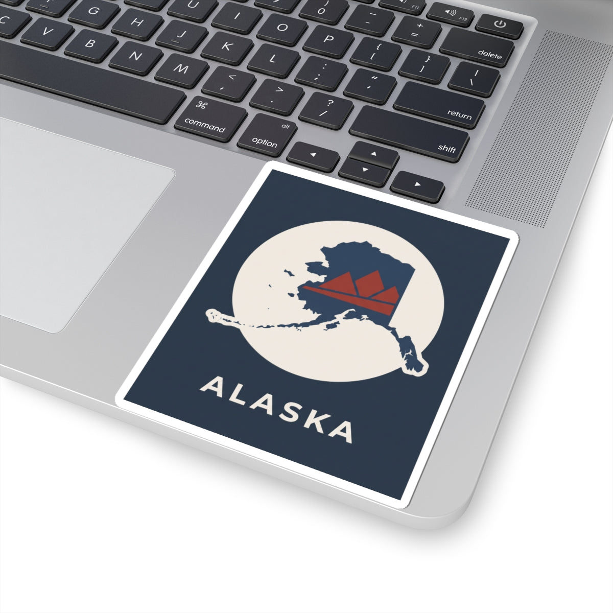 Alaska map badge sticker on a laptop with retro mountain in red and navy on cream circle