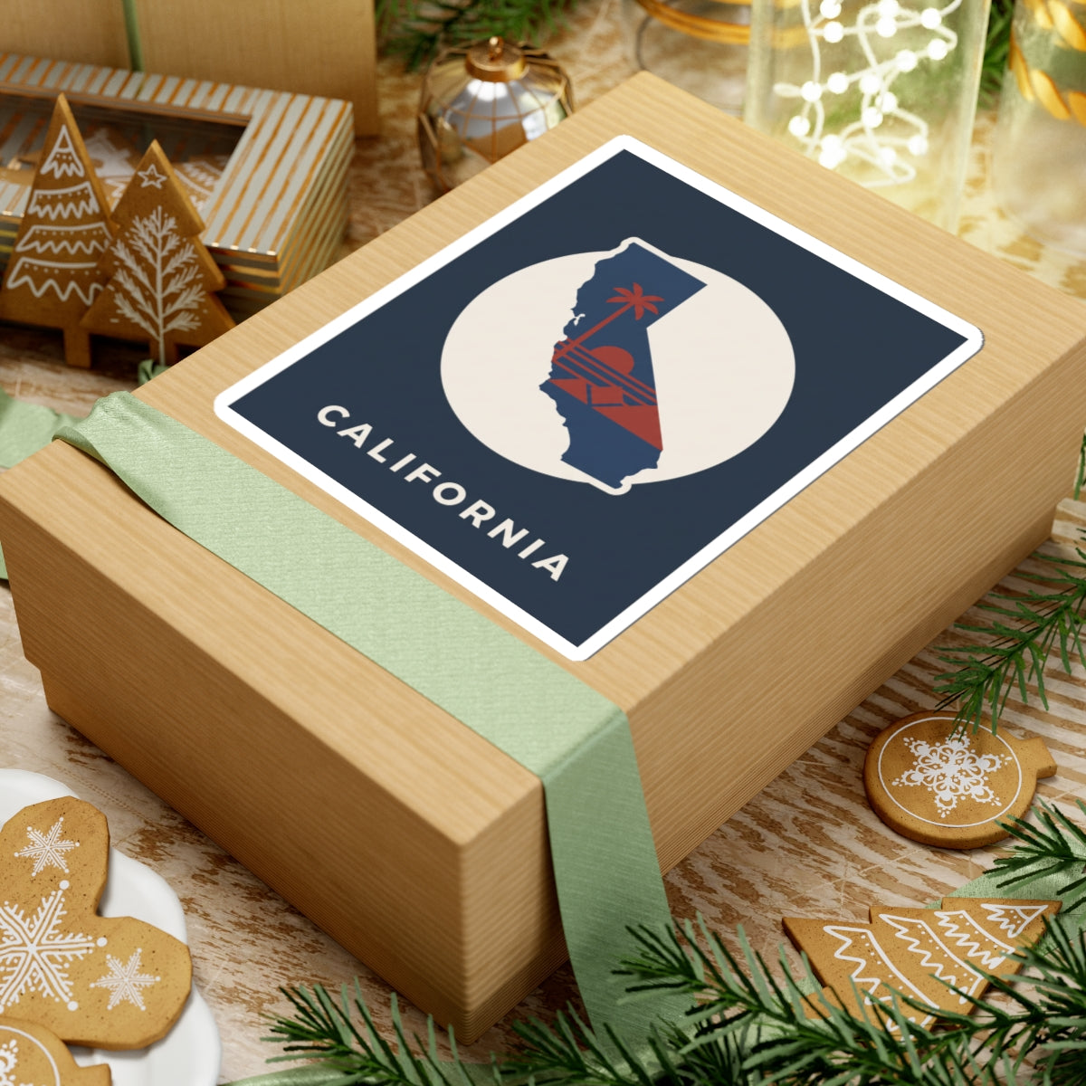 California silhouette sticker on wrapped gift: navy square frame, white circle, red sunset, "CALIFORNIA"