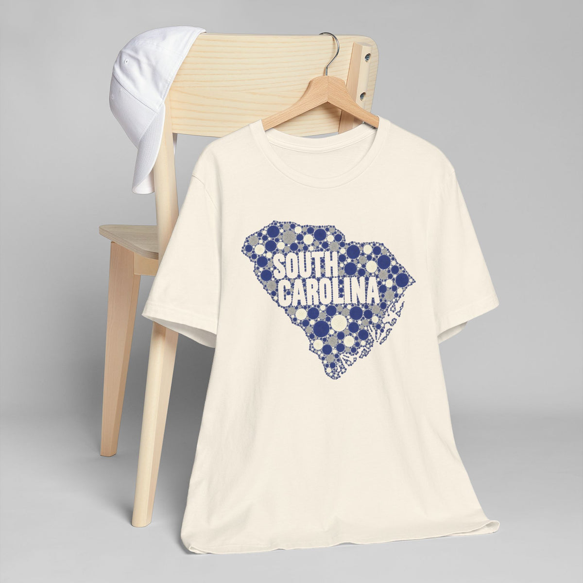 Cream T-shirt with blue dotted South Carolina outline and text graphic on front.