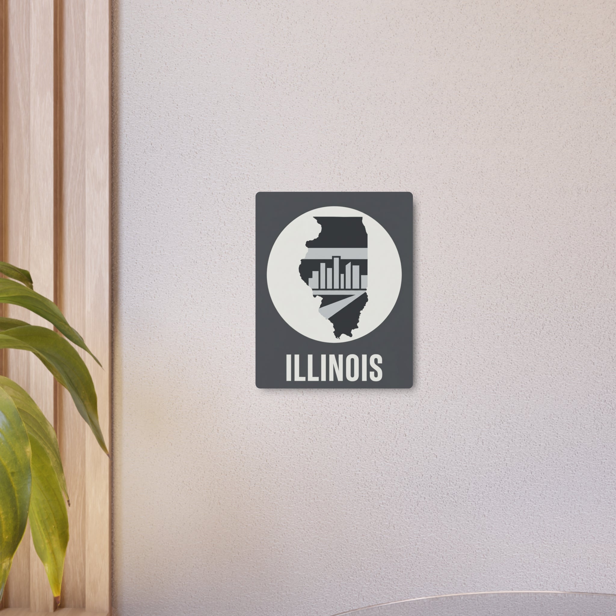 Small Illinois metal wall art on wall: square panel with circular state silhouette and “ILLINOIS”.