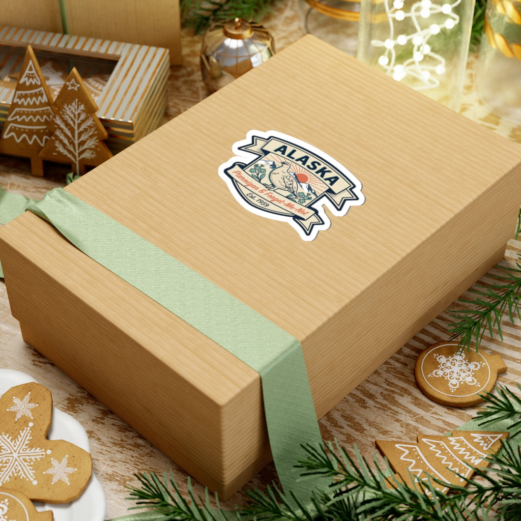 Die-cut Alaska badge sticker on a tan wrapped gift box with ptarmigan and Est. 1959