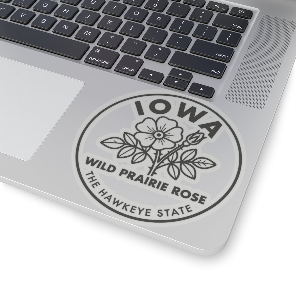 Circular vinyl decal on laptop lid with Iowa lettering and wild prairie rose text
