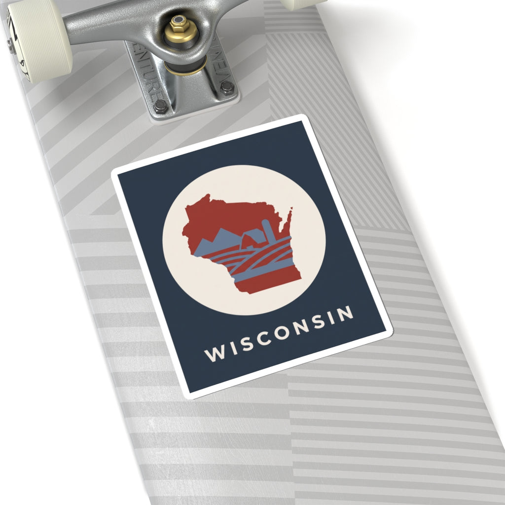 Wisconsin badge sticker on notebook: red map in cream circle with WISCONSIN text