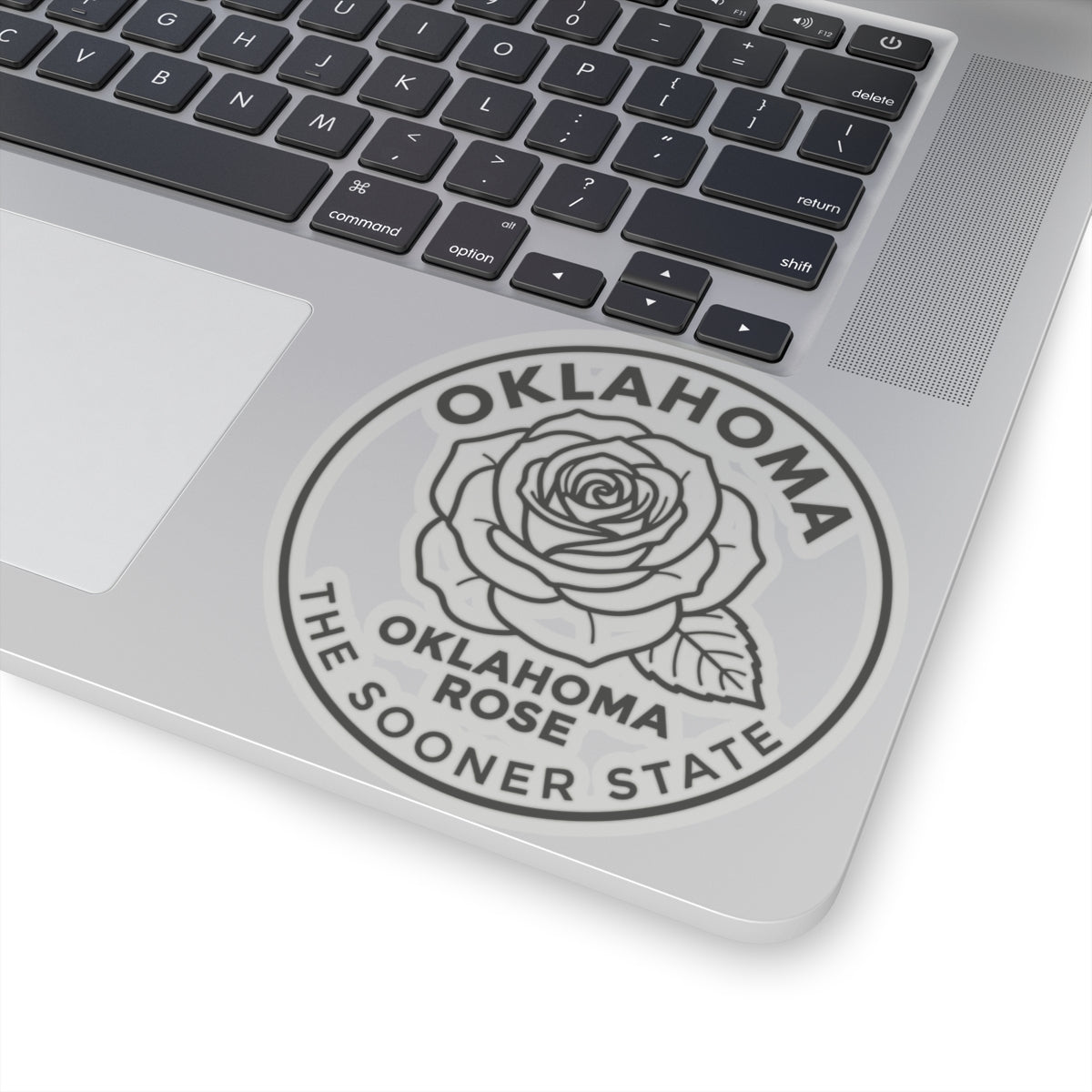 Transparent vinyl Oklahoma rose sticker on laptop lid, round seal showing rose and state text