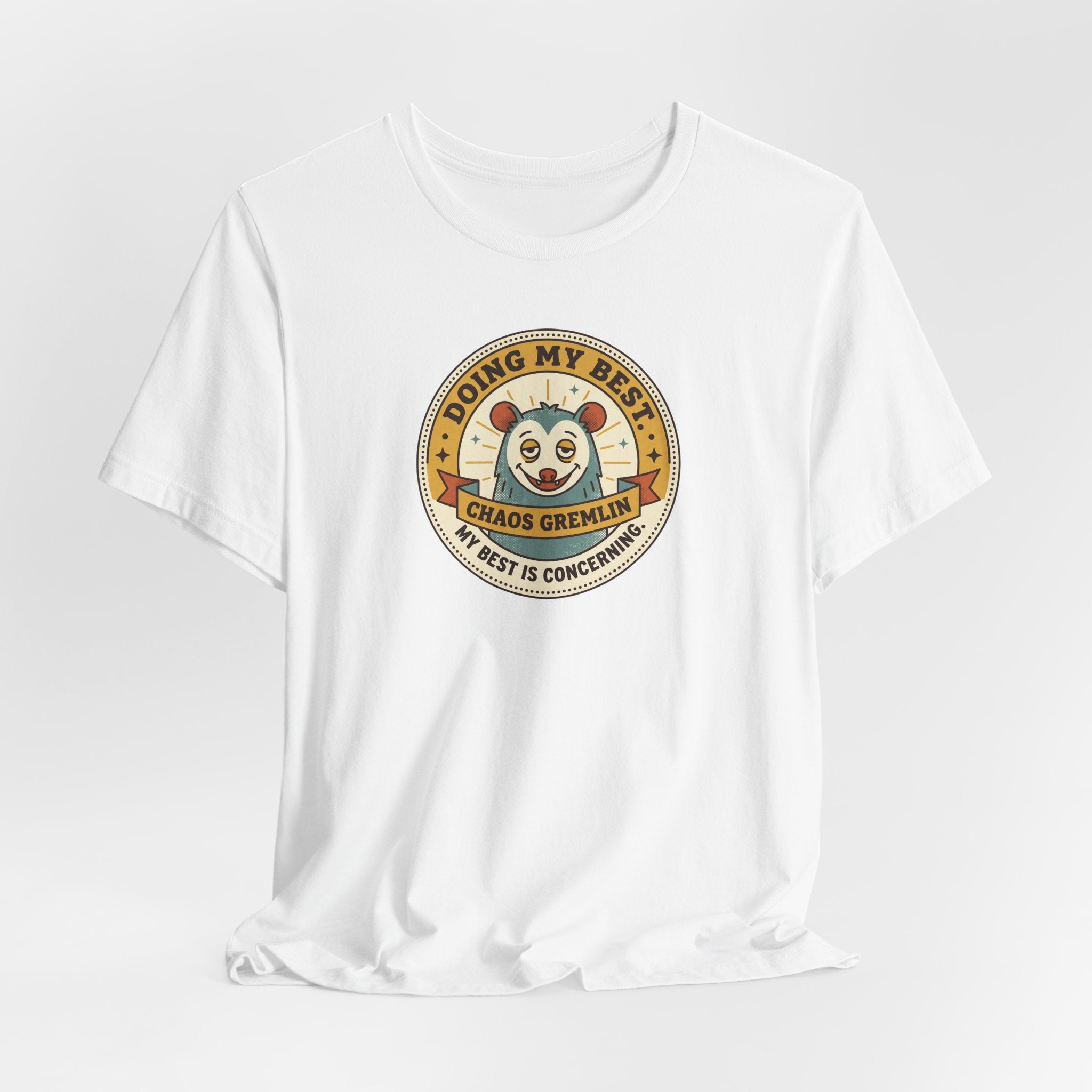 White T-shirt with round cartoon gremlin badge graphic centered on the chest