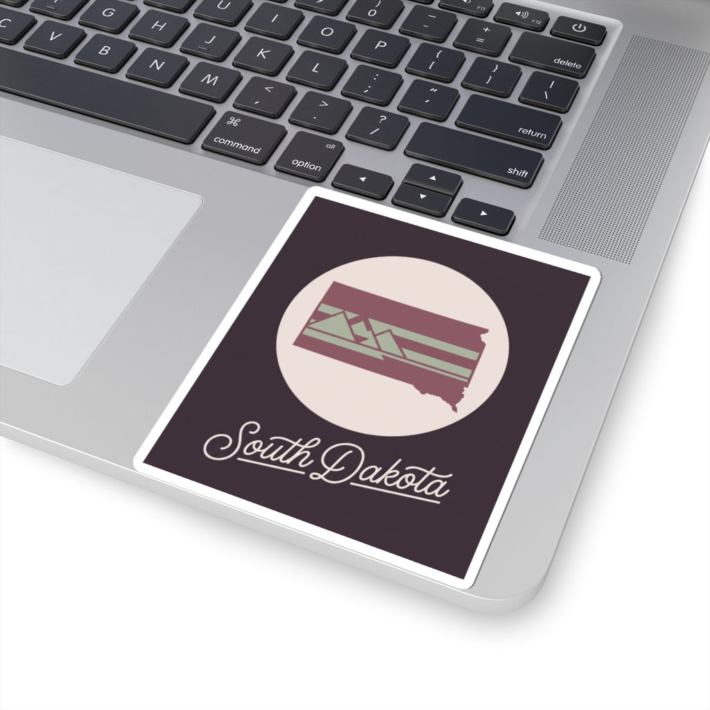 South Dakota kiss-cut decal on a laptop keyboard, dark purple rectangle with cursive text