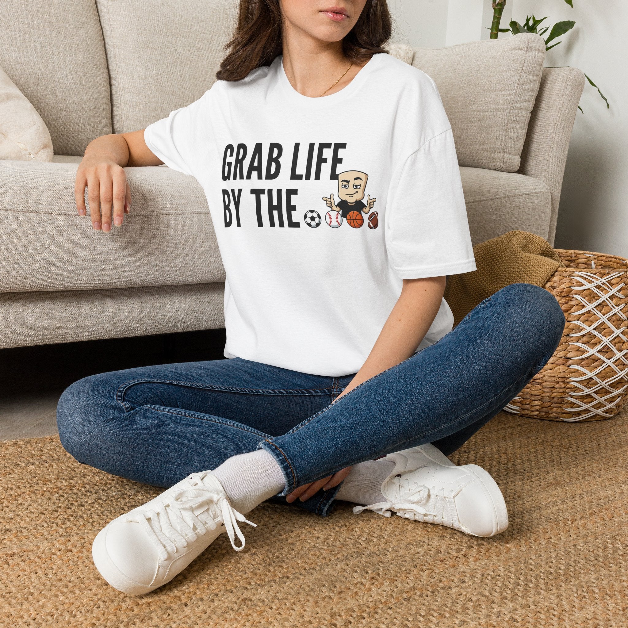 White graphic T-shirt worn with jeans; motivational text and sports ball characters