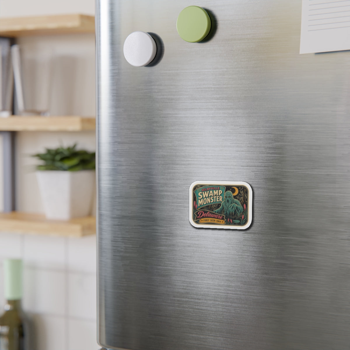 Rounded die-cut magnet adhered to stainless fridge door, featuring “Delaware” retro creature art.
