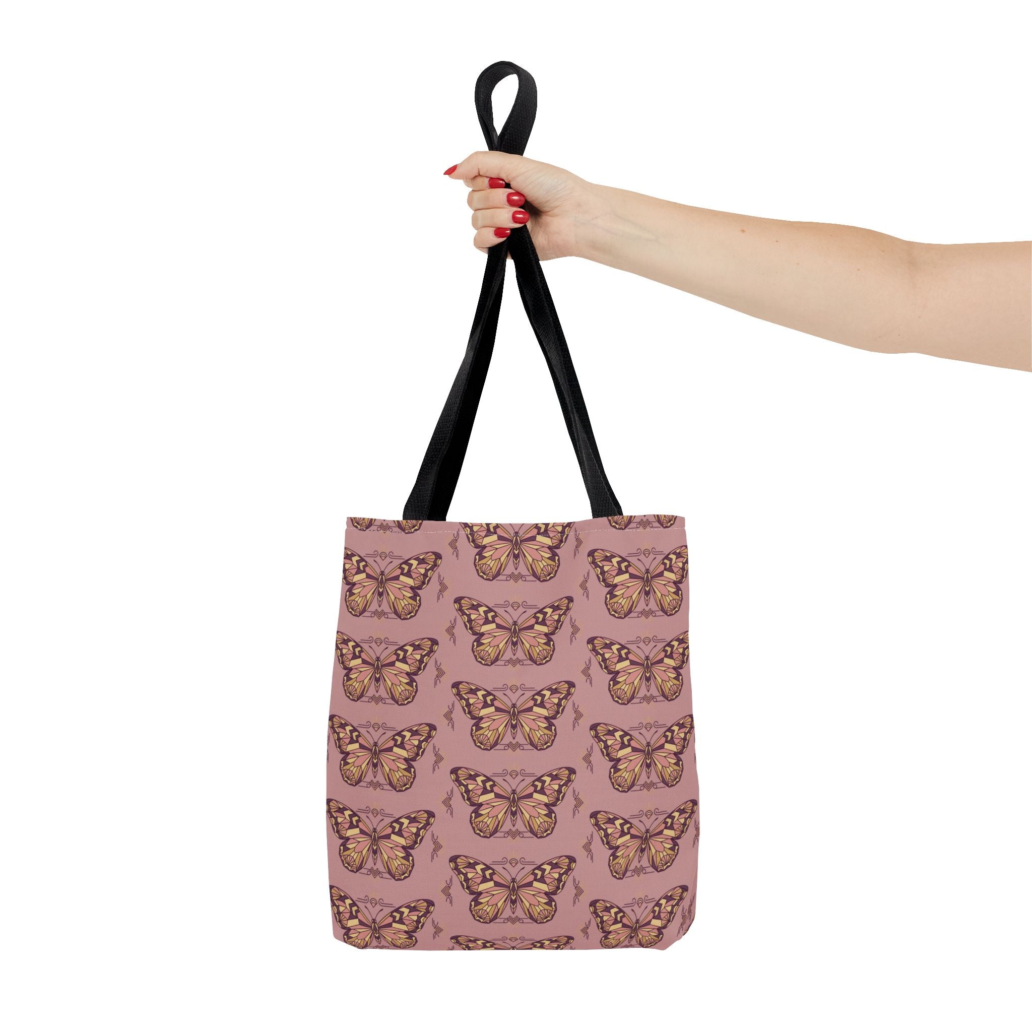 Pink vintage butterfly tote bag with black handles, held up by one hand