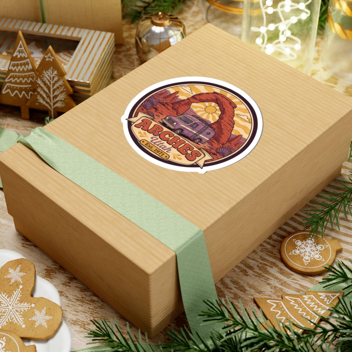 Round sticker on gift box: purple camper van under red rock arch, 'Est. 1971'