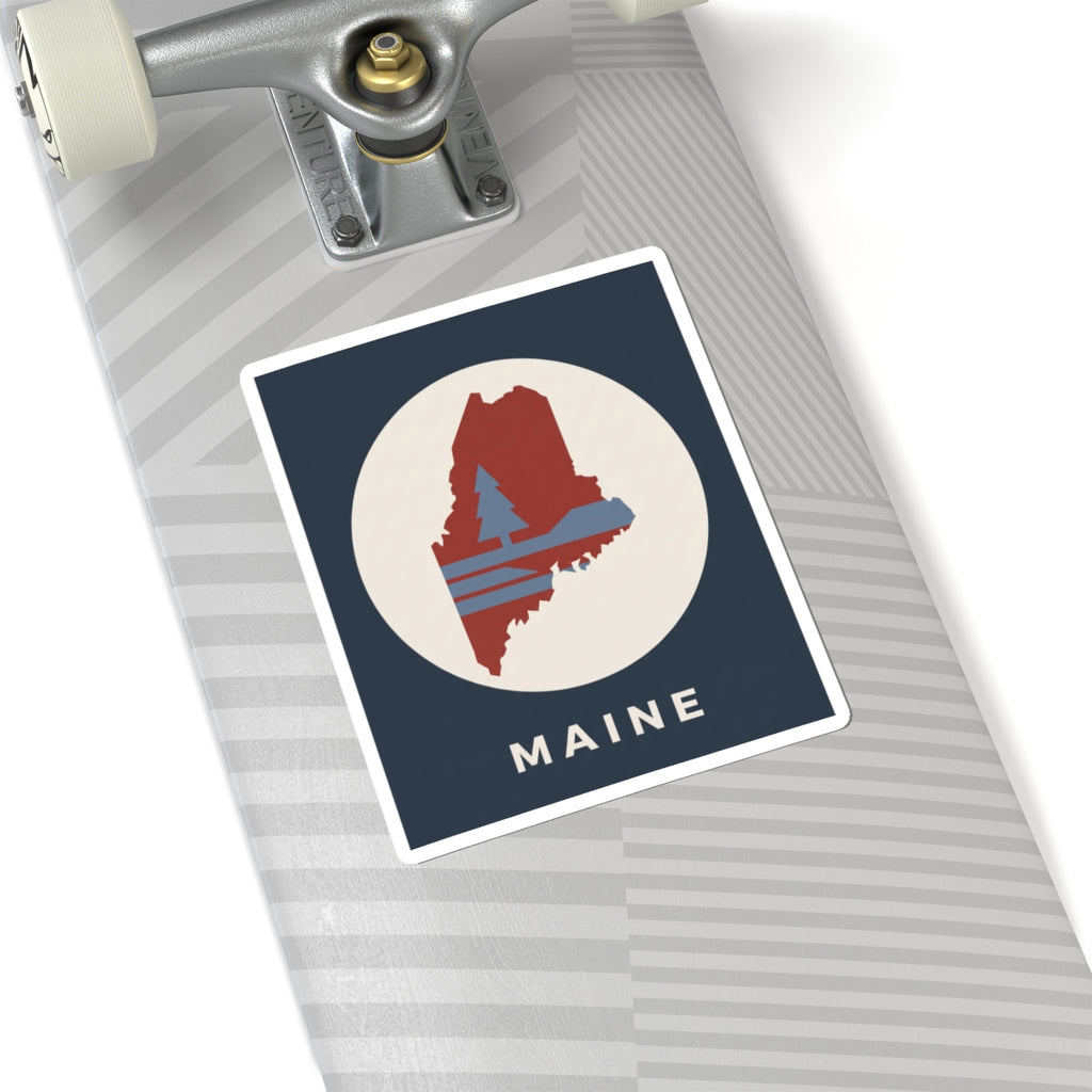 Maine silhouette sticker on notebook or folder: navy square with red Maine outline and “MAINE”