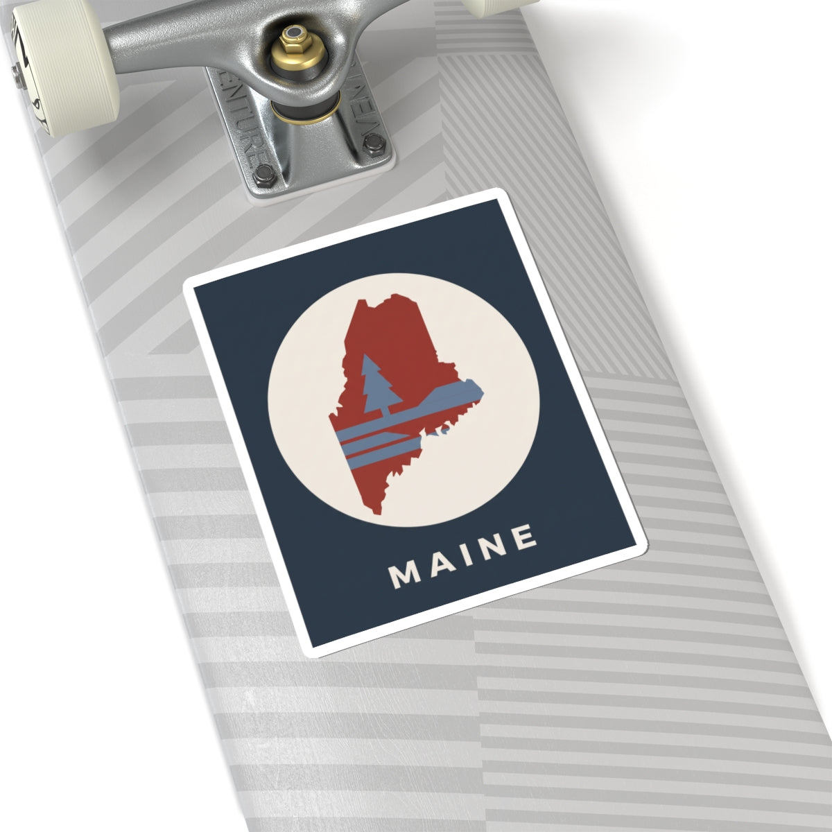Maine silhouette sticker on notebook or folder: navy square with red Maine outline and “MAINE”