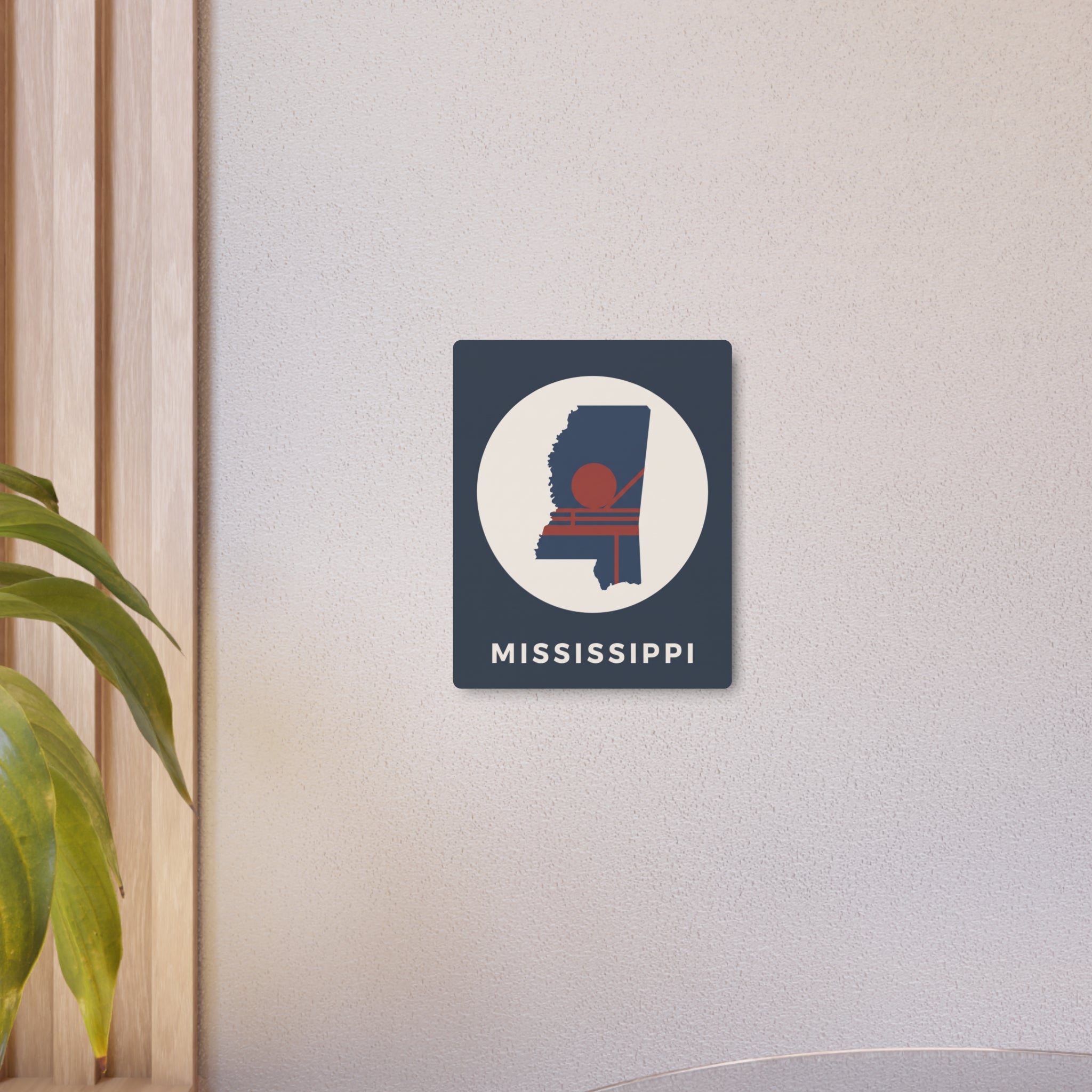 Small Mississippi metal art sign on wall: square dark blue with circular silhouette and “MISSISSIPPI”.