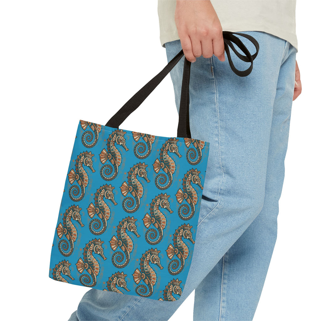Ocean blue seahorse patterned tote bag with black handles, held by a person