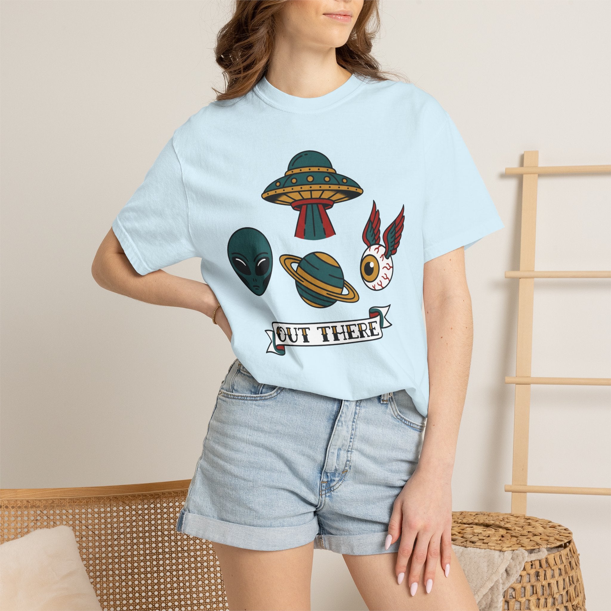 Light blue crewneck T-shirt with UFO and alien patch graphic, worn with denim shorts.