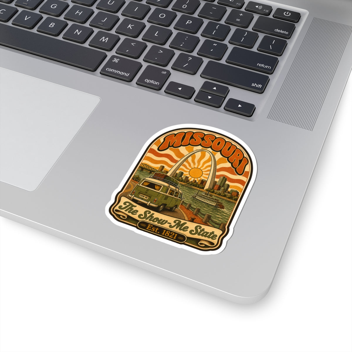 Missouri retro roadtrip sticker on laptop keyboard, arch sun over bus and riverboat