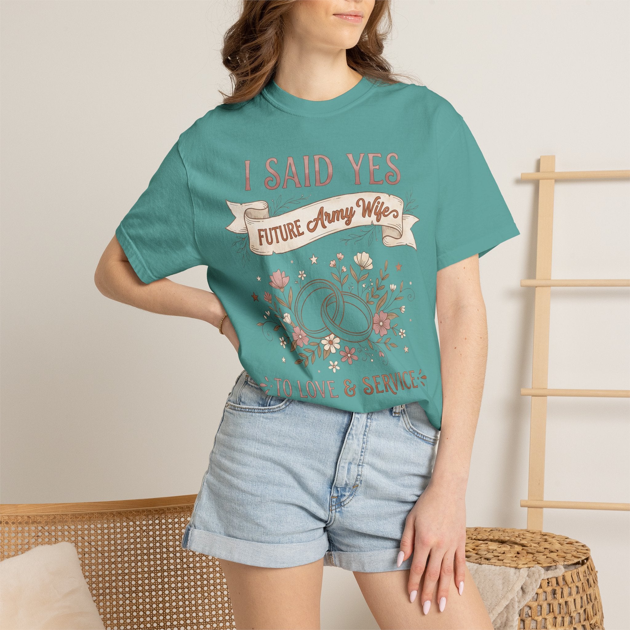 Teal T-shirt worn by a model, front floral ribbon text graphic visible.