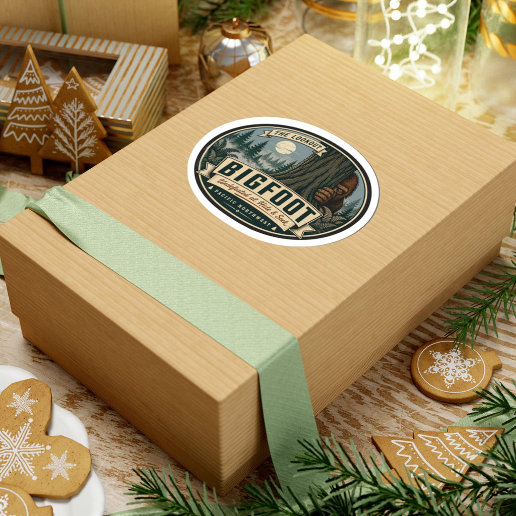 Round kiss-cut Bigfoot outdoor logo vinyl sticker on tan gift box with green ribbon
