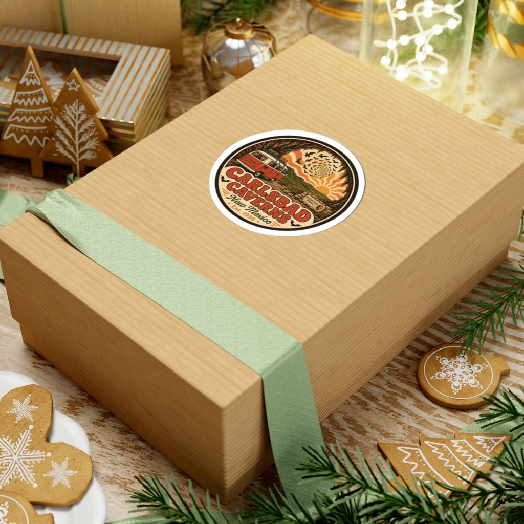 Round Carlsbad Caverns sticker placed on a wrapped gift box; orange camper van in cave scene